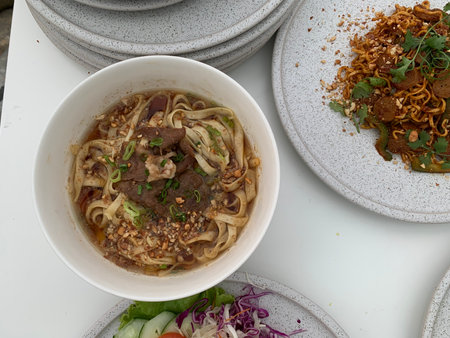 Thai noodle soup with beef in white bowl on the tableの写真素材