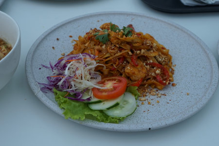 Thai spicy noodle with vegetables on white plate.