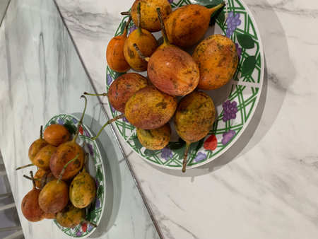 Passion fruit in a ceramic bowl on a marble countertop.