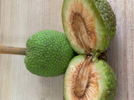 Close up view of green fruit with wooden spoon on wooden background.
