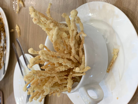 Crispy fried onion rings in white cup with spoon and forkの写真素材