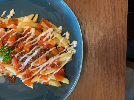 French fries with bolognese sauce on the blue plate.