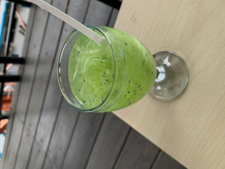 A glass of matcha green tea smoothie in a cafe.の写真素材
