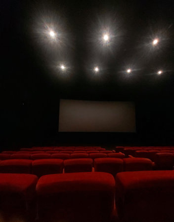 Cinema auditorium with red seats and white screen in the darkの写真素材