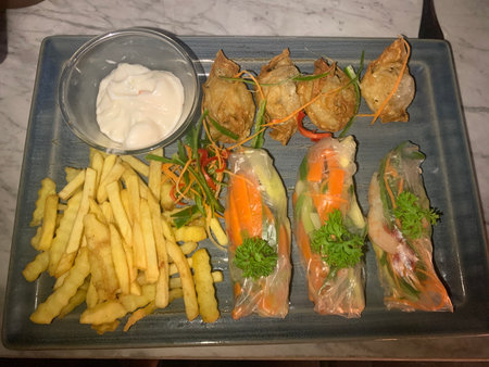 Fried spring rolls and French fries with mayonnaise sauce.