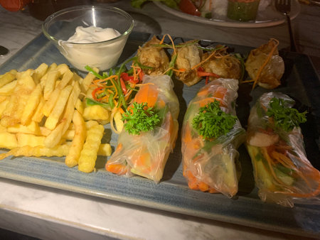 Fried spring rolls with vegetables and french fries in a restaurant.