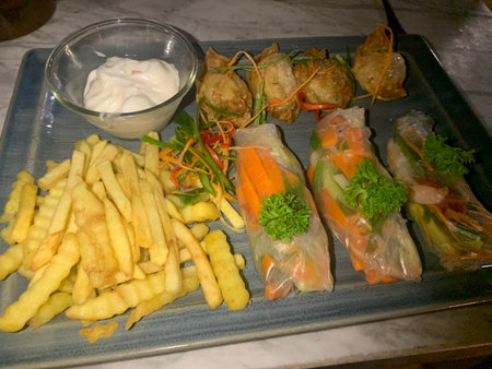 Fried spring rolls with dipping sauce and French fries on a plate