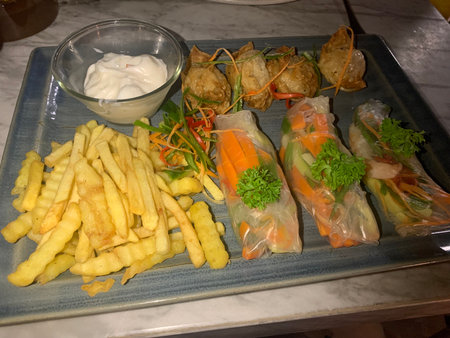 Fried spring rolls and French fries with sour cream.