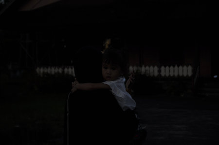 Silhouette of a little girl sitting on her father's lapの写真素材