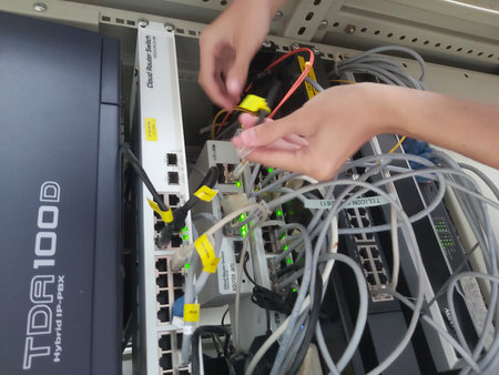 Unidentified technician working in server room with network cables connected.