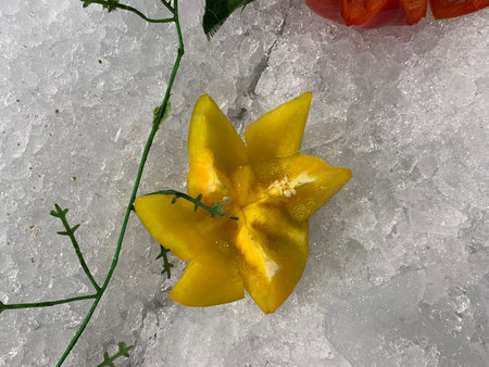 Close up of fresh yellow bell pepper on crushed ice with green leavesの写真素材