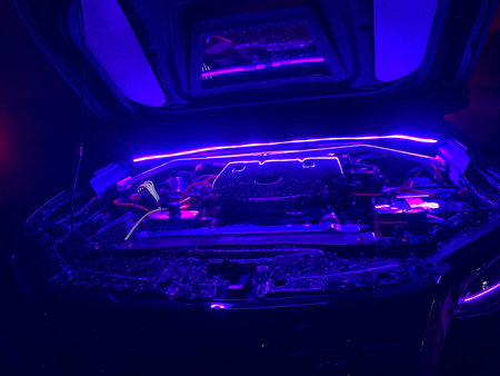 Close up shot of the engine of a modern car in neon light