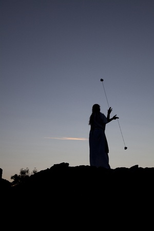 siluette of a woman playing with poi on a castle wall at sunsetの写真素材