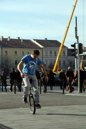 young man  riding a monocycle on a street in a crowded cityのeditorial素材