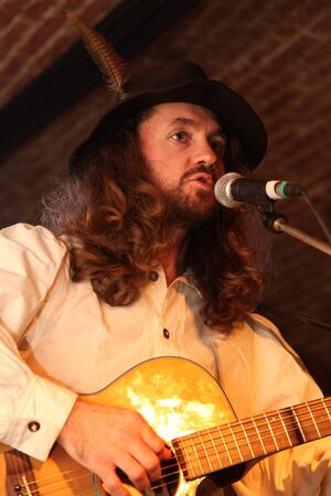 man with hat and feather singing live at a concert in romaniaのeditorial素材