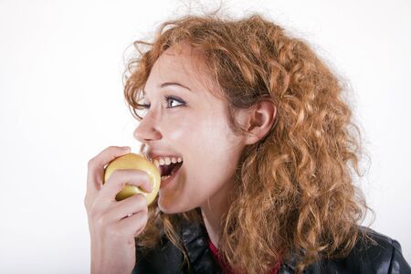 Young atractive woman eating an apple on a white background