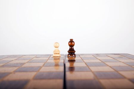 chess pawn going head to head with a horse on a white nackgroundの写真素材