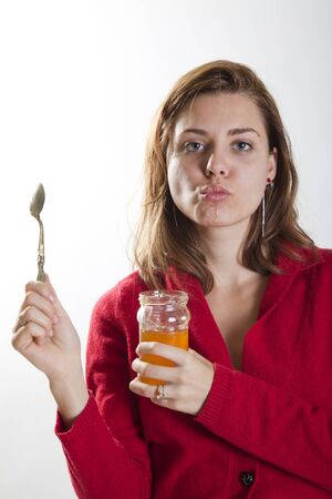 young woman holding a jar of honey and a spoon in her hands looking sexyの写真素材