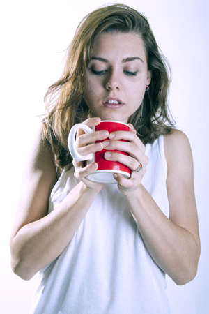 young woman drinking a cup of coffeein the morning pijamasの写真素材