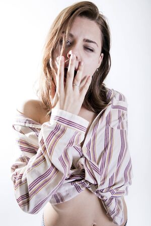 young attractive woman yawning in the morning in pajamas looking sadの写真素材