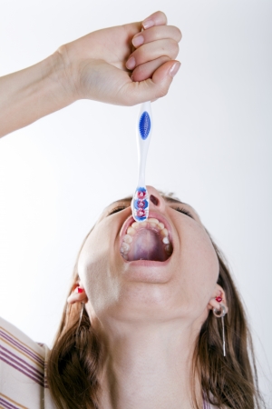 young attractive woman swallowing a tooth brushの写真素材