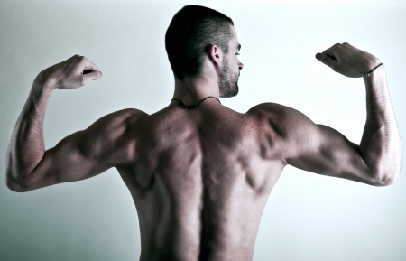 muscular young man back isolated on silver backgroundの写真素材