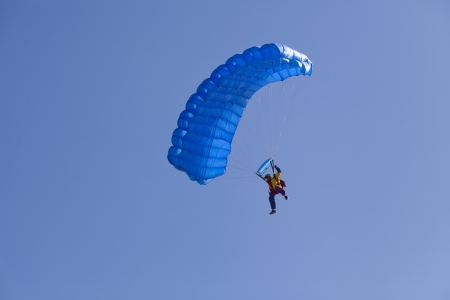 man with parachute flying on a clear blue perfect skyの写真素材