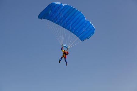 man on clear blue sky with parachute from behindの写真素材