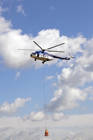 rescue helicopter in the air with human cargo hanging fom a ropeのeditorial素材