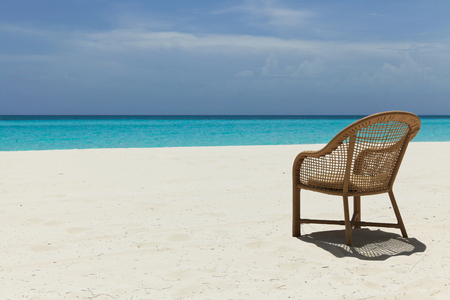 empty chair on a beach with white sand and blue waterの写真素材