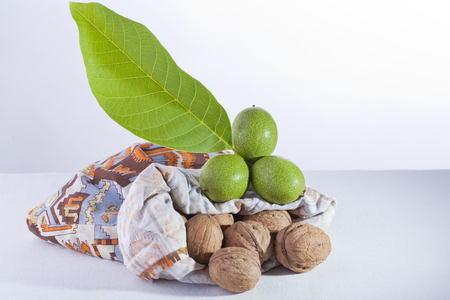 green and ripe walnuts with a leaf from a bagの写真素材