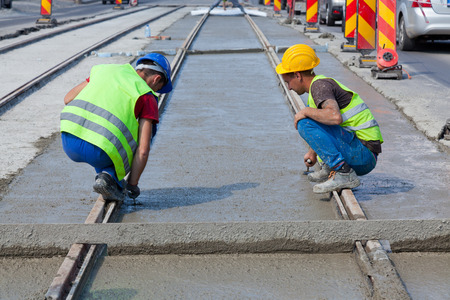 construction team pouring concrete on a road with boots and protection gearのeditorial素材