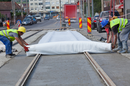 men covering fresh wet cement on the road with clothのeditorial素材