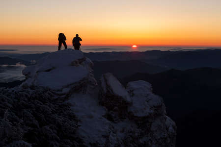 photographer men on snow mountain at red sunrise