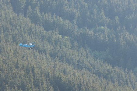 Small airplane flying over a forest in the Carpathian Mountains.の写真素材