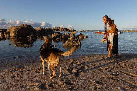 Sexy Hispanic woman on the beach with dog next to water in Galicia Spain on a sunny summer dayの写真素材