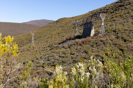 Abandoned steel structure with towers from industrial coal mining cableway in mountains of Asturias Spain in Tormaleo on a sunny spring day with flowersの写真素材