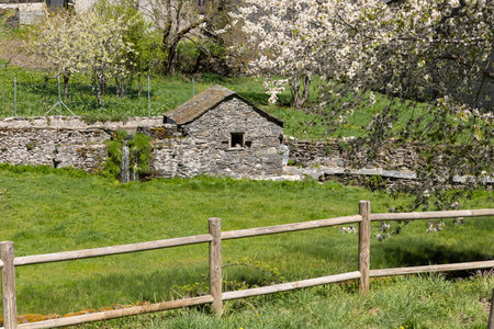 Traditional small stone water mill on a bright sunny spring day next to stream with green vegetation in Tormaleo village Asturias province of Spain.の写真素材