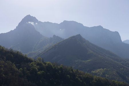 Mountain landscape with peak and cloud on a bright sunny spring day with green vegetation and blue sky in Picos de Europa National Park in the north of Spain.の写真素材