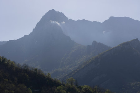 Mountain landscape with peak and cloud on a bright sunny spring day with green vegetation and blue sky in Picos de Europa National Park in the north of Spain.の写真素材