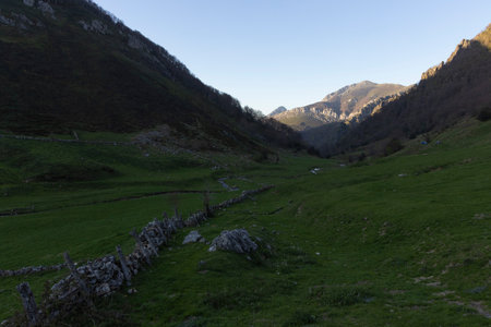 Mountain landscape with peak and cloud on a bright sunny spring day with green vegetation and blue sky in Picos de Europa National Park in the north of Spain.の写真素材