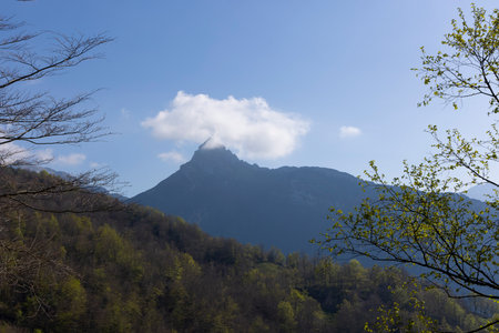 Mountain landscape with peak and cloud on a bright sunny spring day with green vegetation and blue sky in Picos de Europa National Park in the north of Spain.の写真素材