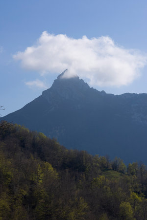 Mountain landscape with peak and cloud on a bright sunny spring day with green vegetation and blue sky in Picos de Europa National Park in the north of Spain.の写真素材