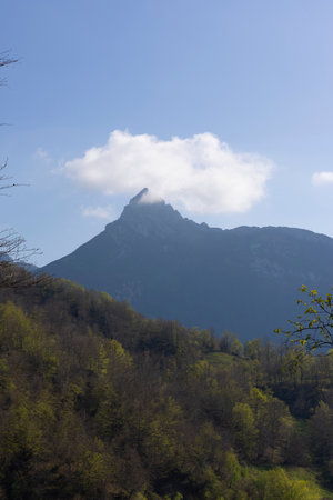 Mountain landscape with peak and cloud on a bright sunny spring day with green vegetation and blue sky in Picos de Europa National Park in the north of Spain.の写真素材