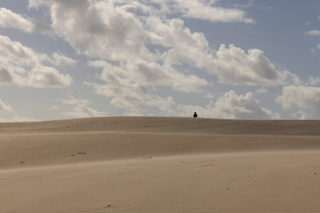 People walking up sand dunes on a bright sunny day in the desert with blue sky.の写真素材
