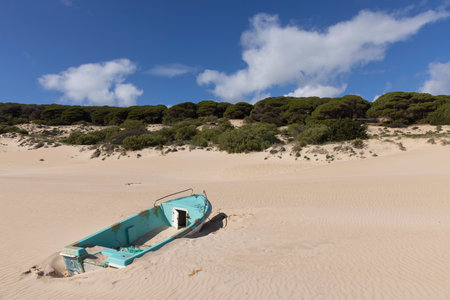 Fishing boat on the sand beach next to ocean at Punta Paloma in Spain on a bright sunny day with blue sky.の写真素材
