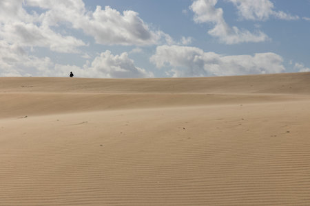 People walking up sand dunes on a bright sunny day in the desert with blue sky.の写真素材