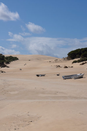 Fishing boat abandoned on the beach next to ocean on the sand with bright sunny day and blue sky.の写真素材