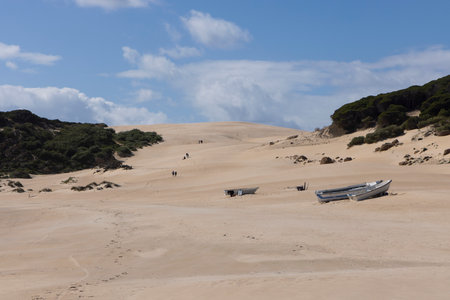 Fishing boat abandoned on the beach next to ocean on the sand with bright sunny day and blue sky.の写真素材