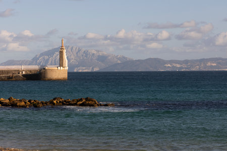 Jesus statue in harbour of Tarifa at the strait of Gibraltar with view to Morocco on a bright sunny day with cloudy sky.の写真素材